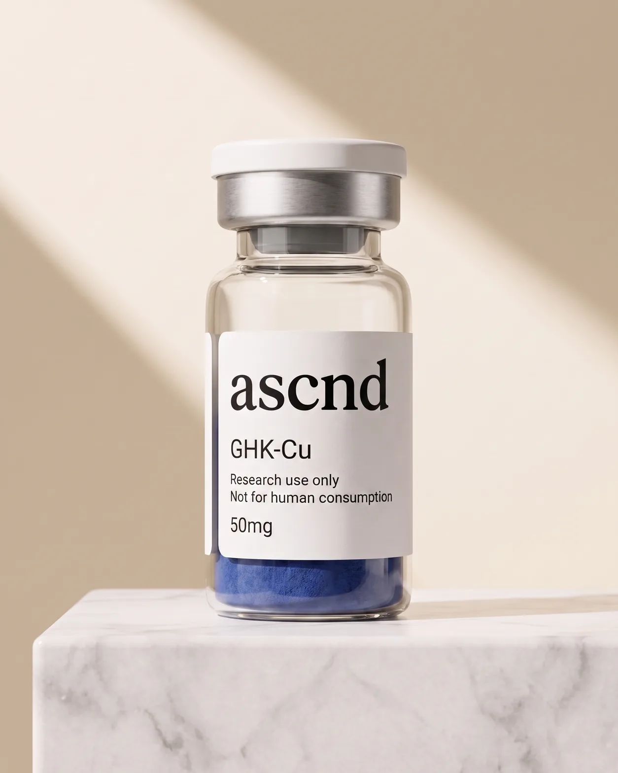 Clear glass ASCND vial of blue lyophilized powder with a research-use-only label, on a marble plinth